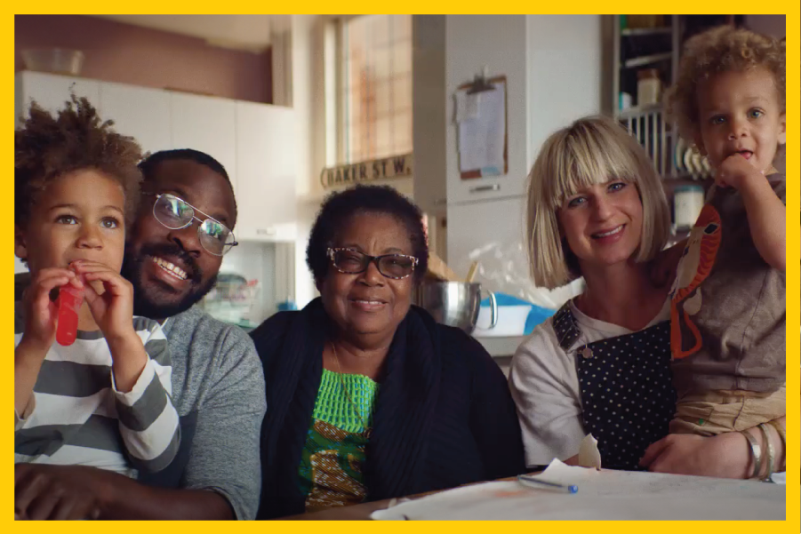 A multi-generational family sitting at the dinner table smiling and looking at the camera